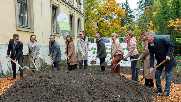 Prominente mit Spaten stehen vor einem Erdhaufen für den obligatorischen Spatenstich für das künftige Naturparkzentrum Steigerwald