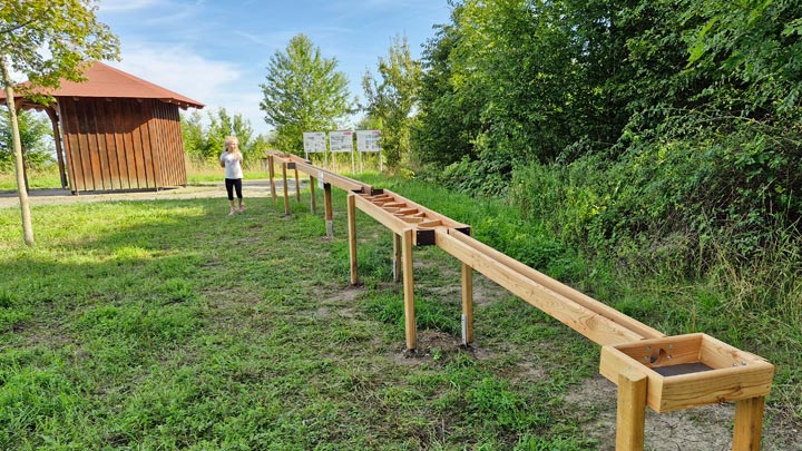 Blick auf eine Holz-Kugelbahn von einer Hecke