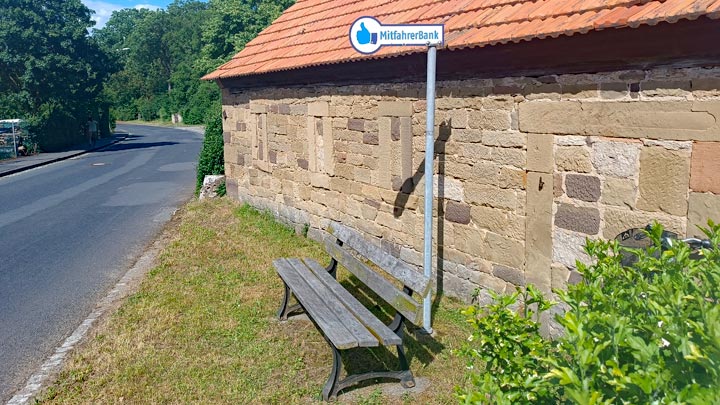 Bild einer Mitfahrerbank an einer Ortsstraße.