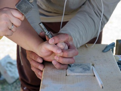 Besucher probieren handwerkliche Tätigkeiten an einem Tisch aus.